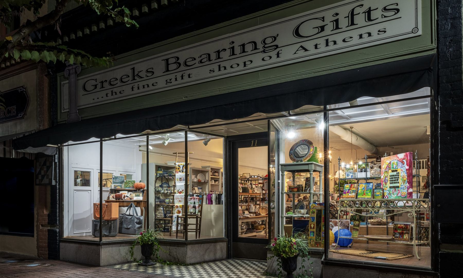Greeks Bearing Gifts storefront at night in Athens, Tennessee.