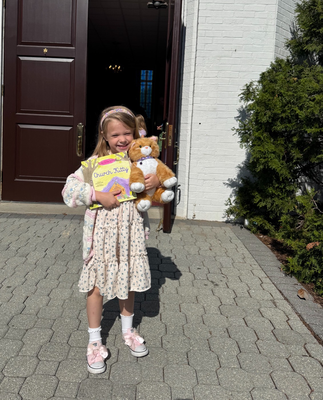 A little reader holding Church Kitty — book and plush together
